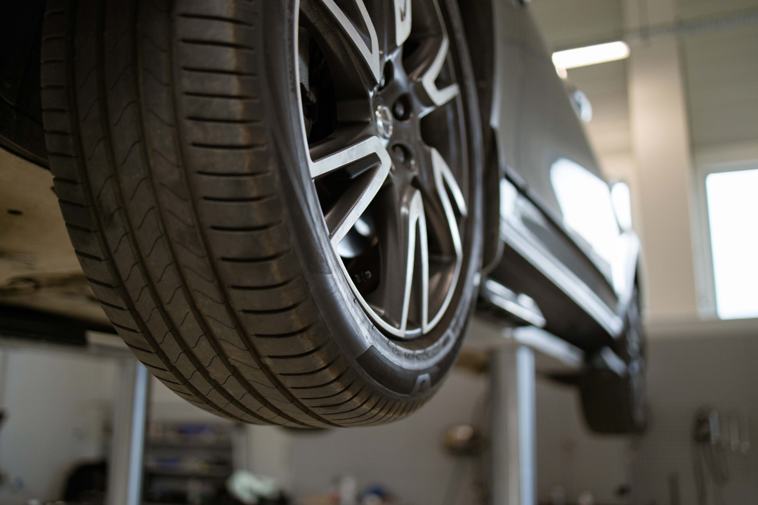 Close-up of car tire on vehicle lift in auto repair shop